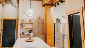 A modern kitchen with wooden beams, a central island with stools, and built-in appliances. - Dockside Suites | The Brix | Pool in Canal Park! (Duluth)
