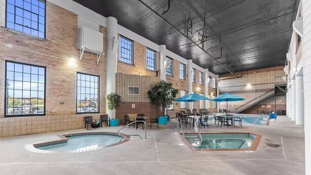 An indoor swimming pool area with multiple pools, lounge chairs, and umbrellas. - Dockside Suites | The Brix | Pool in Canal Park! (Duluth)