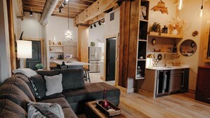 A modern living room with a large sectional sofa, a coffee table, and a kitchen in the background. - Dockside Suites | The Brix | Pool in Canal Park! (Duluth)