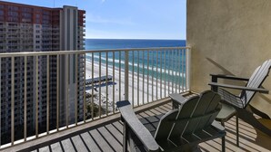 Ein Balkon mit Blick auf Strand und Meer, ausgestattet mit zwei Stühlen und einem Tisch.