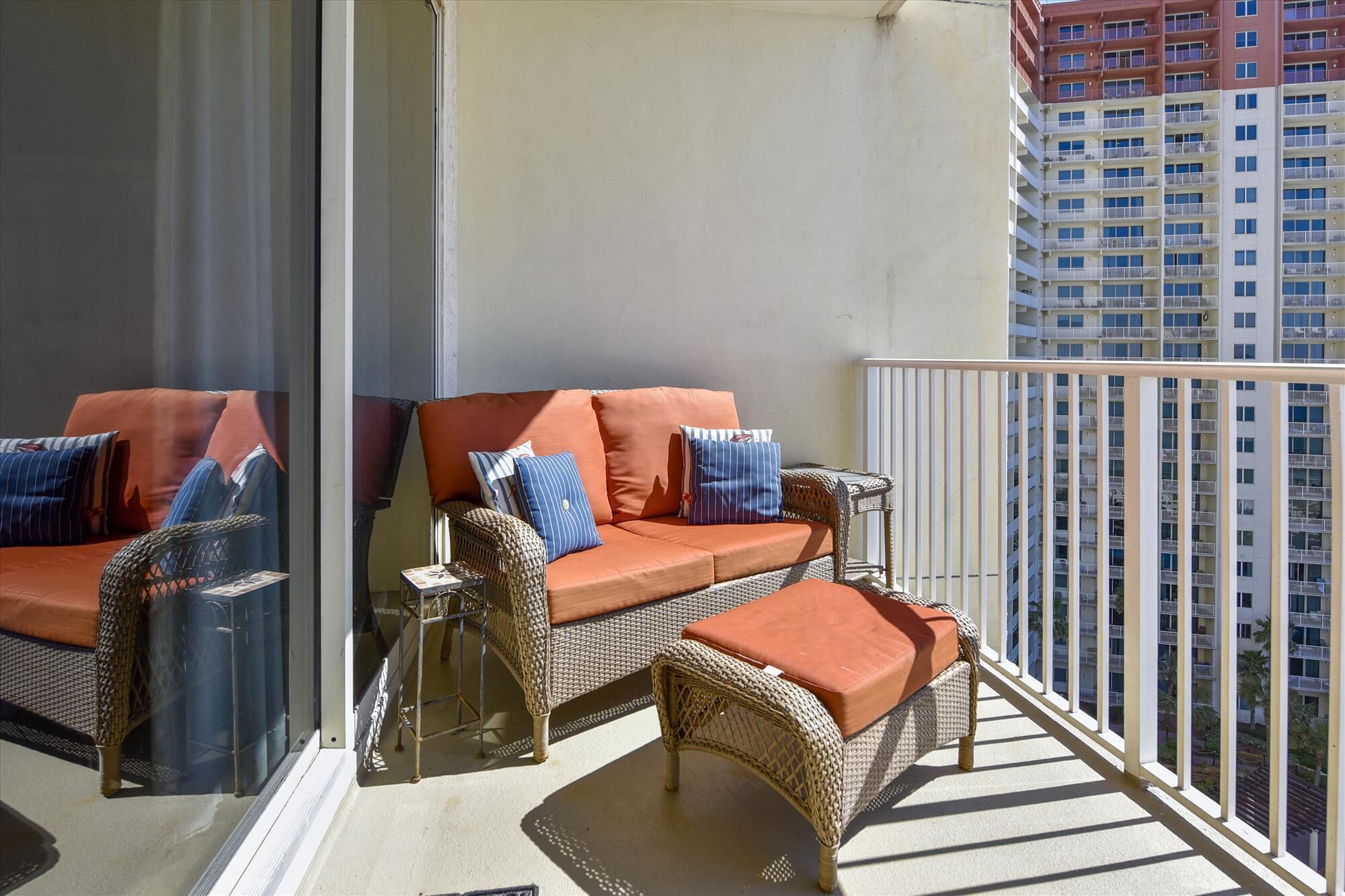 A balcony with wicker furniture, including a sofa and two chairs, and a railing.