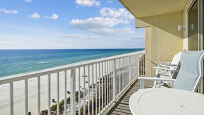 A balcony with a view of the beach and ocean.