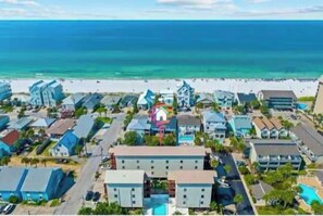 Un hôtel situé sur la côte, composé de plusieurs bâtiments, avec une plage en arrière-plan et un ciel dégagé.