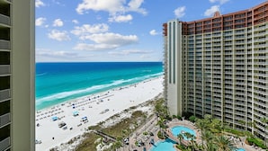 A high-rise hotel with a beach view, a pool, and a beach area with umbrellas.