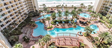 Un hotel con varios balcones, una piscina central y vista al océano.