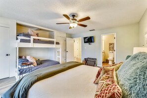 A bedroom with a bunk bed, a ceiling fan, a television, and a bathroom visible through an open door. - Edgewater Villas #2108 - 2 Bedroom/2Bath Sleeps 8.  Free Fun! (Panama City Beach)