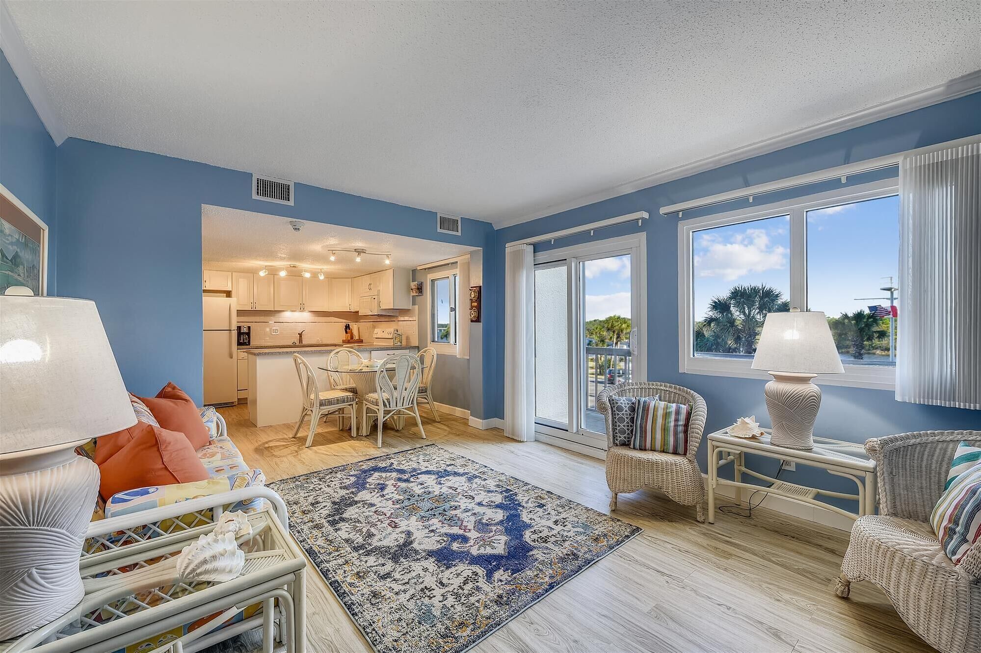 A spacious living room with a large window, a dining area, and a kitchen.
