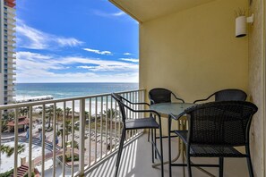 Ein Balkon mit Tisch und Stühlen, der Blick auf einen Strand und den Ozean gewährt.