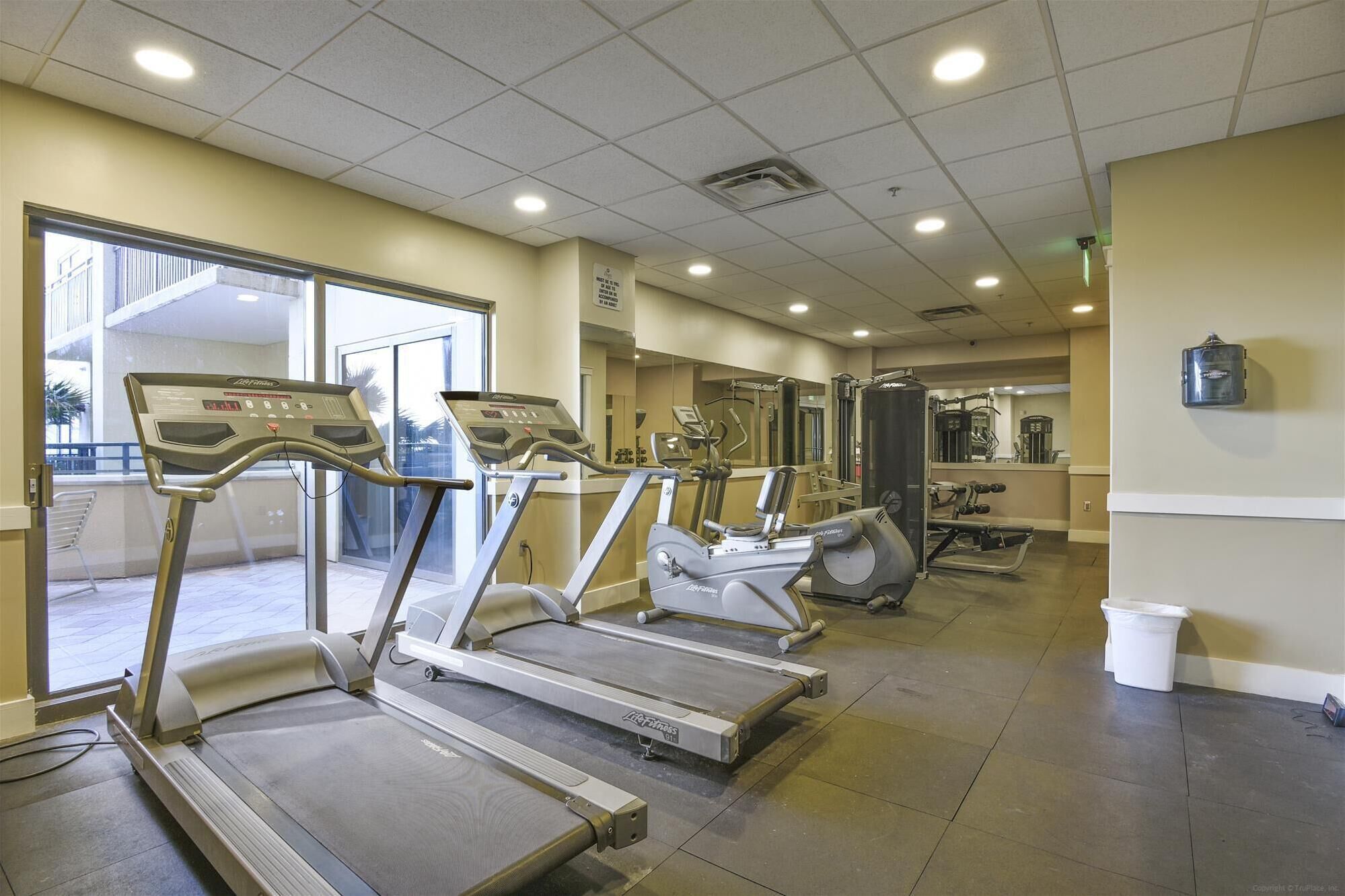 Ein Fitnessstudio mit Laufbändern, Kraftgeräten und einem Spiegel.