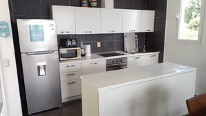 A modern kitchen with a refrigerator, microwave, toaster, kettle, and stove. - Romance Nest in Samana 7-202 (Samaná)