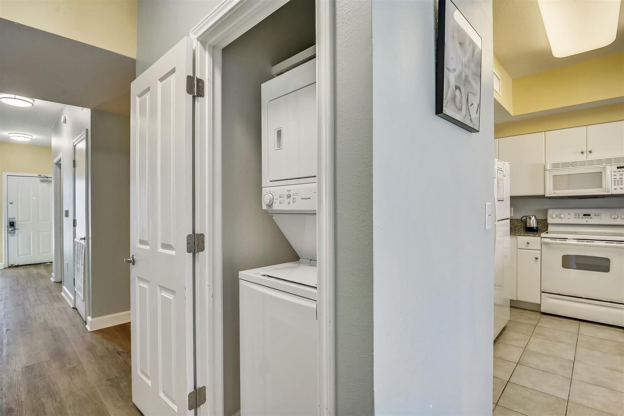 A kitchen with white appliances, including a microwave and oven, and a refrigerator.