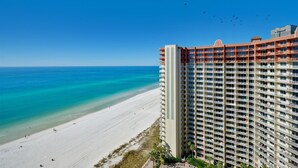 A high-rise hotel with multiple balconies overlooking a beach.