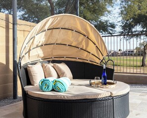 A round outdoor seating area with a canopy, cushions, and a bottle. - Copper Cactus House: Pool, Spa, Golf! (Queen Creek)