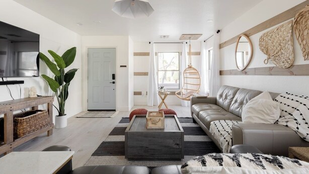 A modern living room with a sofa, coffee table, TV, and a hanging chair.