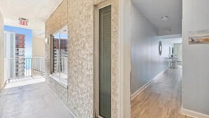 A corridor with a marble wall, a door, and a view of other buildings.