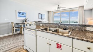 A modern kitchen with granite countertops, stainless steel appliances, and a view of the ocean.