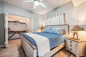 Ein Schlafzimmer mit einem Bett, einem Nachttisch, einer Lampe, einem Deckenventilator und einem Kleiderschrank.