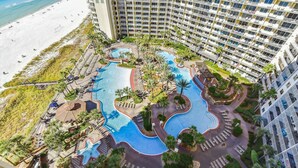 Een resort met een groot zwembadgedeelte, diverse zwembaden en een strand.