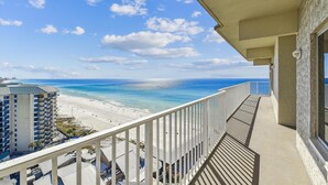 Een balkon met uitzicht op strand en zee.