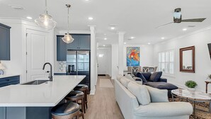 A modern kitchen with a central island, bar stools, and pendant lighting.