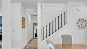 A modern interior with a staircase, a dining area, and a kitchen visible in the background.