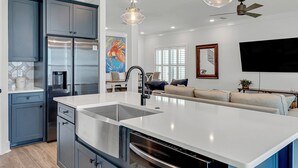 A modern kitchen with a large island, stainless steel appliances, and pendant lighting.