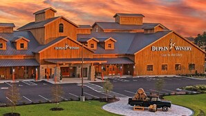 Un edificio de madera grande con el nombre 'Dupin Winery' y el lema 'God be the Glory'.