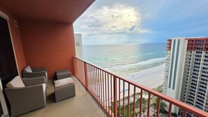 Ein Balkon mit Korbmöbeln mit Blick auf einen Strand und hohe Gebäude.