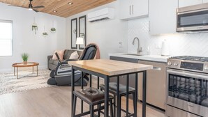 A modern kitchen with white cabinets, a Bosch oven, and a dining area with a wooden table and black chairs. - Kordeluxe Row #3 Studio Townhouse (Cedar City)