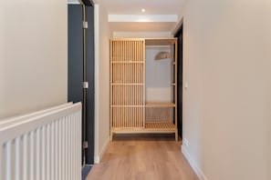 Un corridoio con un armadio in legno, un termosifone e una rastrelliera appendiabiti.