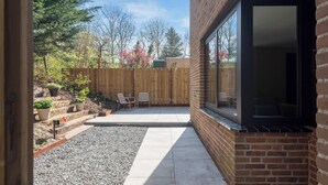 A backyard with a wooden fence, a patio with chairs, and a gravel area. - Blissea - Comfortable stay, top location (Zandvoort)