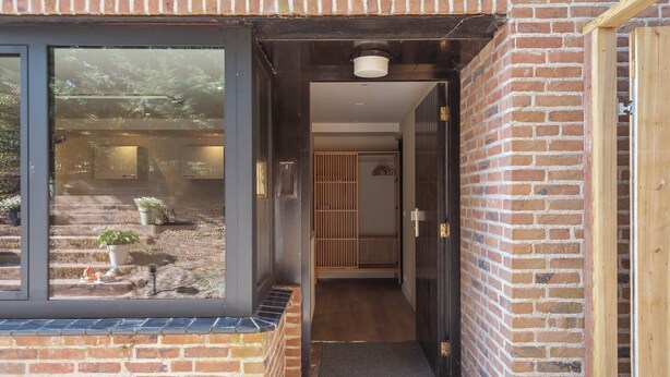 A brick exterior with a large window, a door, and a small outdoor area with steps and potted plants. - Blissea - Comfortable stay, top location (Zandvoort)