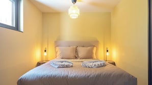 A neatly made bed with a headboard, two bedside lamps, and a hanging light fixture. - Blissea - Comfortable stay, top location (Zandvoort)
