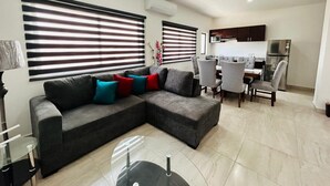 A modern living room with a sectional sofa, dining area, and kitchen. - Aleman Apartments  (Mazatlán)