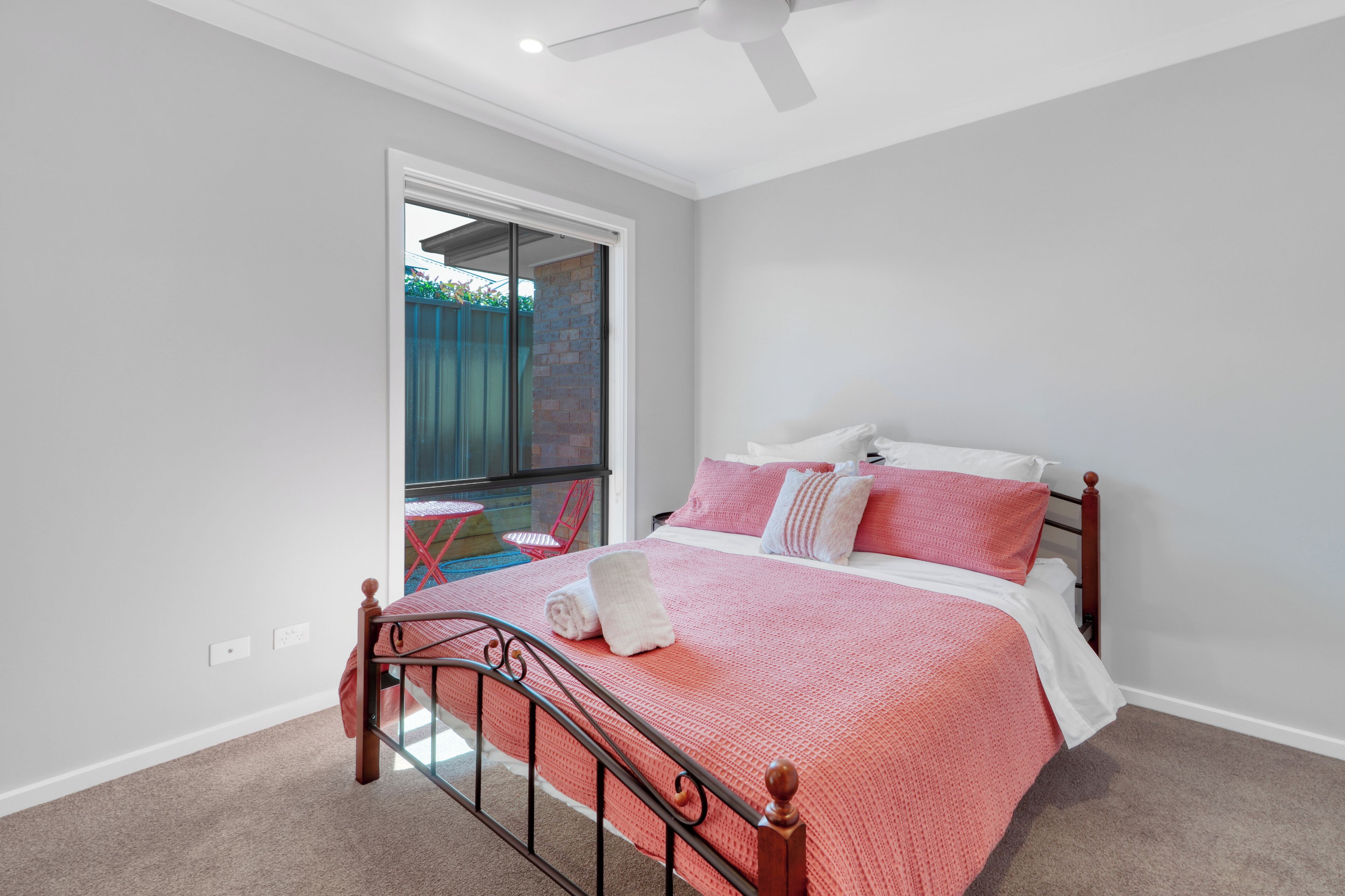 Ein Schlafzimmer mit Bett, Deckenventilator und Blick ins Freie.