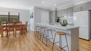 A modern kitchen with a central island, bar stools, and a dining area with wooden chairs. - Apres - Dog Friendly (Mansfield)