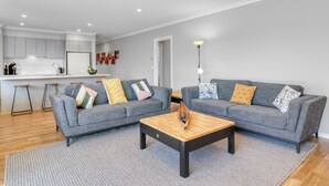 A modern living room with two grey sofas, a wooden coffee table, and a kitchen in the background. - Apres - Dog Friendly (Mansfield)