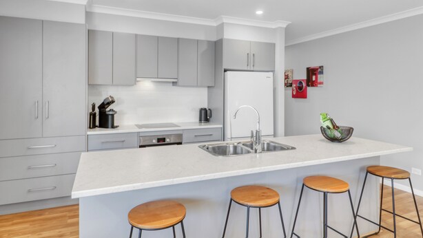 A modern kitchen with grey cabinets, a white countertop, and four wooden bar stools. - Apres - Dog Friendly (Mansfield)