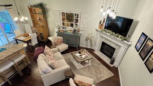 A spacious living room with a fireplace, a dining area with a wooden table and chairs, and a cozy seating area with a sofa and armchairs.
