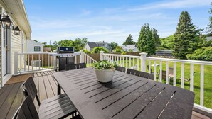 Eine Terrasse mit Grill, einem Blumentopf und einem Tisch mit Stühlen.