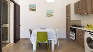 A compact kitchen with a dining table, chairs, and a washing machine. - Apartment with large outdoor space available (Agropoli)