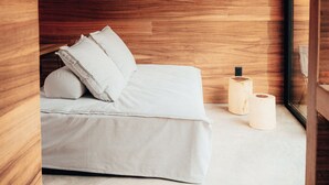 Un dormitorio con techo de madera, cama con ropa blanca y dos lámparas de noche.
