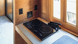 Une cuisine compacte avec un plafond en bois, une cuisinière intégrée et une fenêtre qui laisse entrer la lumière naturelle.