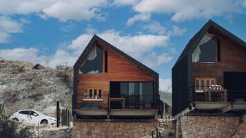 A modern two-story house with a stone foundation, large windows, and a wooden exterior.