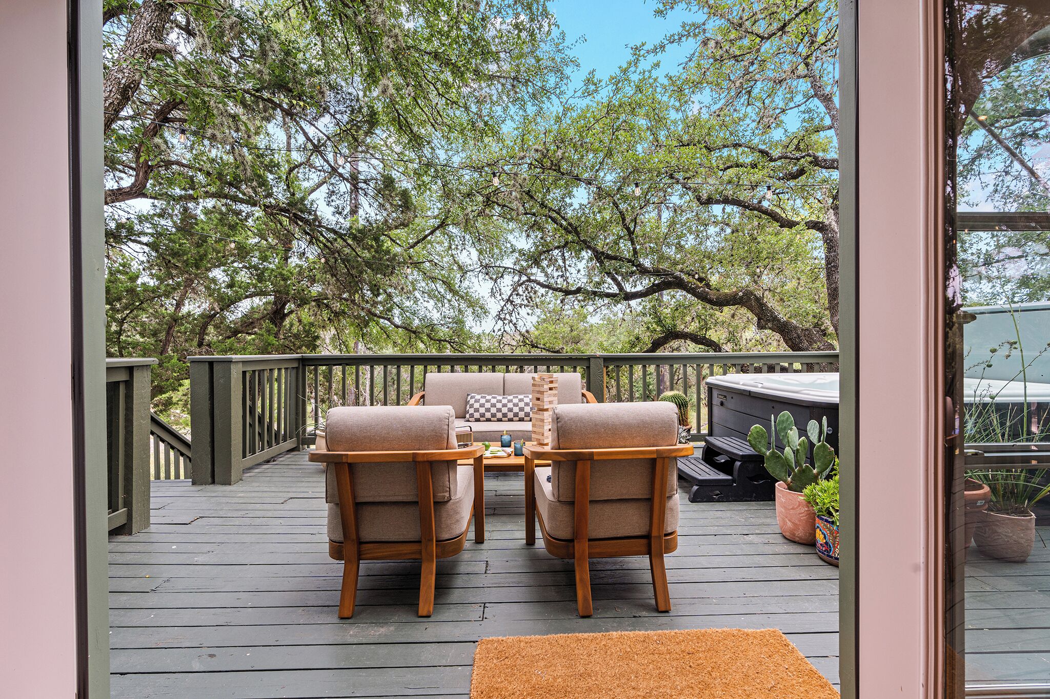 A deck with a sofa, two chairs, a table, and potted plants.