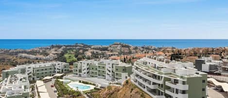 Una zona residencial costera con edificios modernos, una piscina y vista al mar.