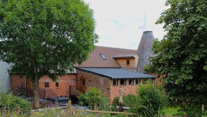 A brick house with a sloped roof, a chimney, and a wooden fence.