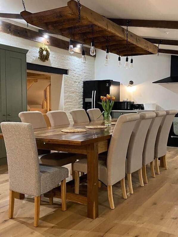 Ein Essbereich mit Holztisch, beigen Stühlen und einer modernen Küche im Hintergrund.