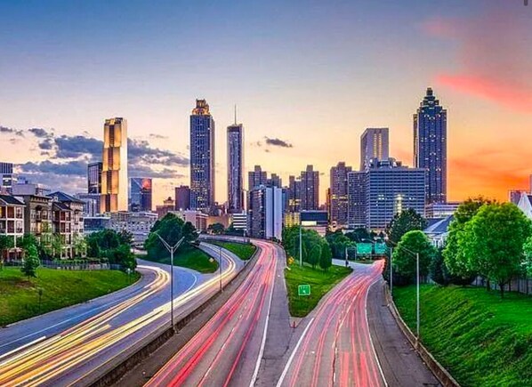 A cityscape with modern high-rise buildings, a curved highway, and green spaces. - Cozy 1-bedroom condo with AC, WiFi in charming Atlanta (Atlanta)
