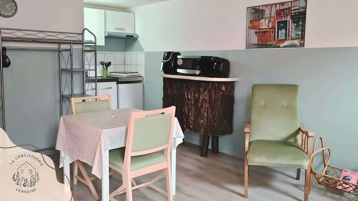 Una cocina compacta con microondas, una pequeña mesa de comedor con sillas y un adorno en la pared.